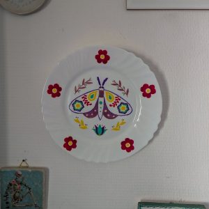 Assiette murale en porcelaine peinte à la main, papillon folk multicolore entouré de fleurs rouges, Fortunae Studio