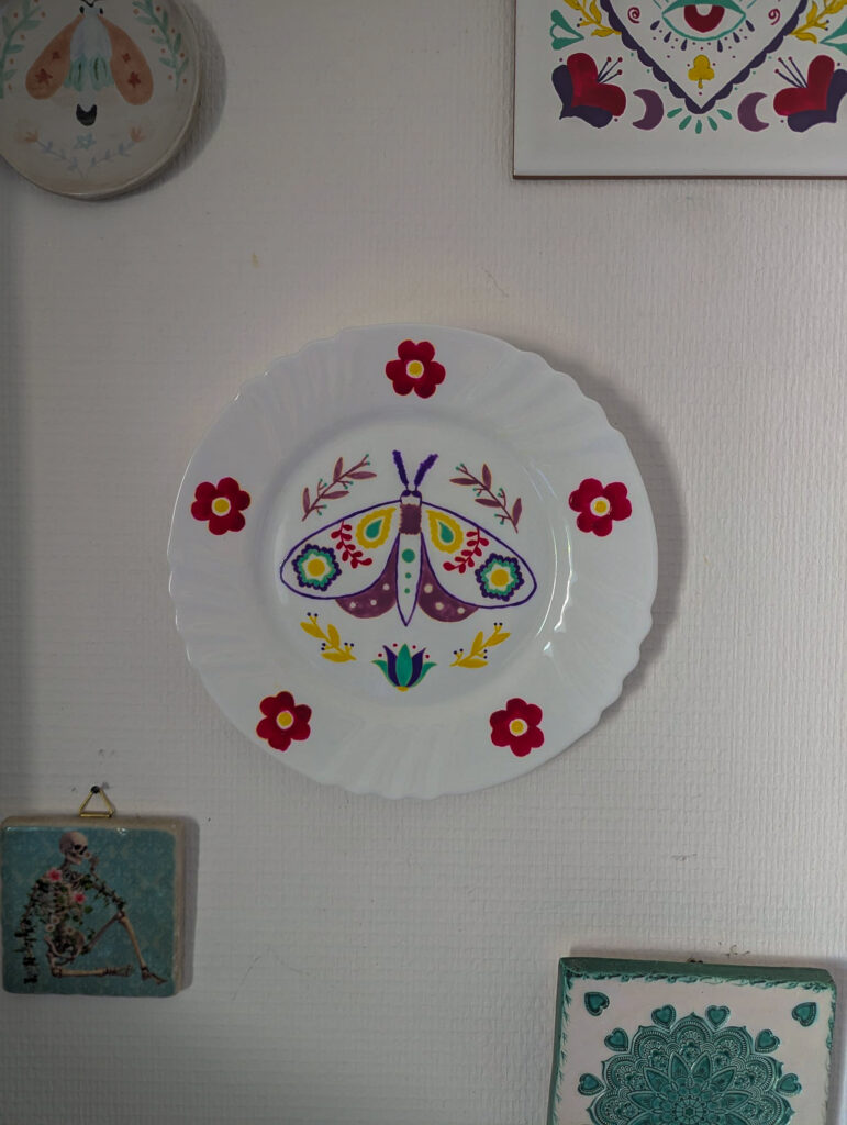 Assiette murale en porcelaine peinte à la main, papillon folk multicolore entouré de fleurs rouges, Fortunae Studio