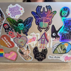 Sticker holographique pailleté ex-voto et Baba Yaga collés sur un ordinateur