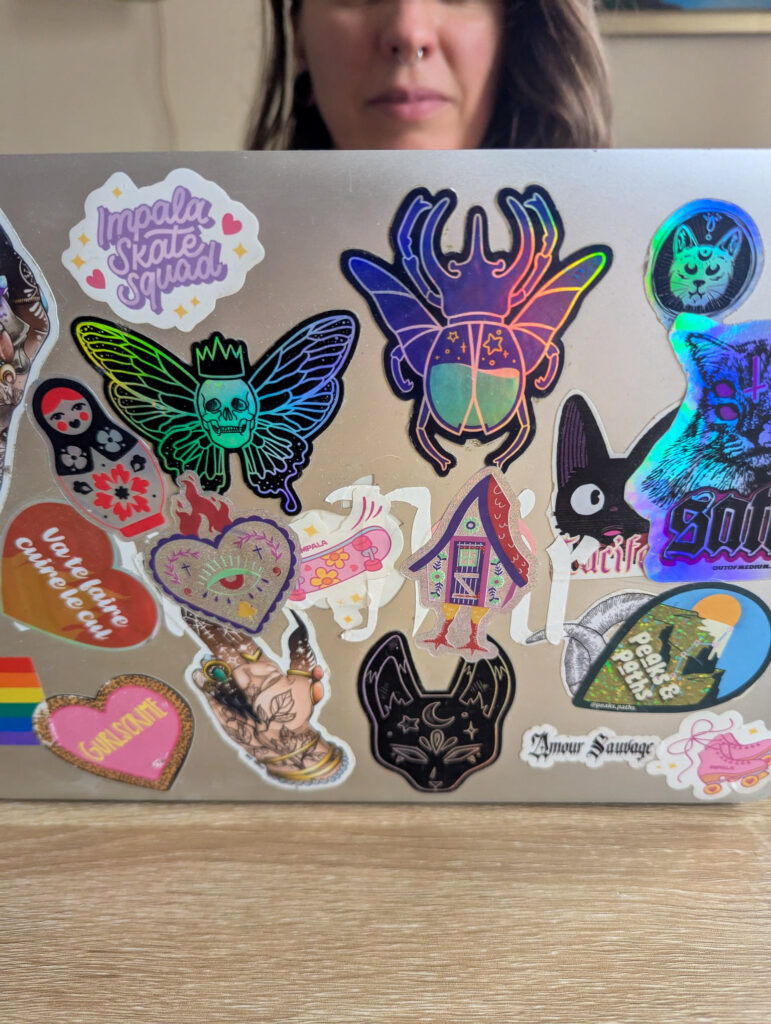 Sticker holographique pailleté ex-voto et Baba Yaga collés sur un ordinateur